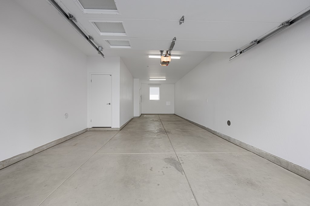 A long, empty hallway with white walls and a concrete floor.